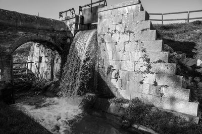 Arch bridge over canal against wall