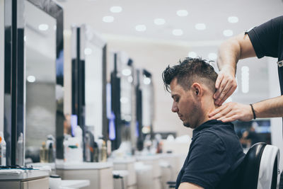 Cropped hands of barber giving massage to customer at salon