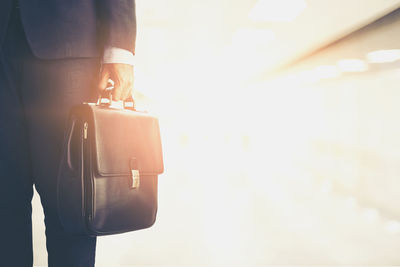 Midsection of businessman holding briefcase