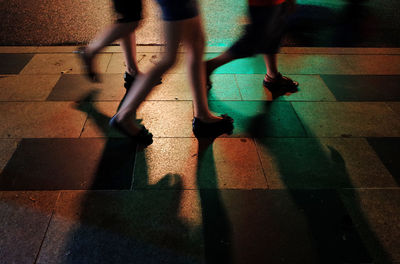 Low section of people walking on footpath at night