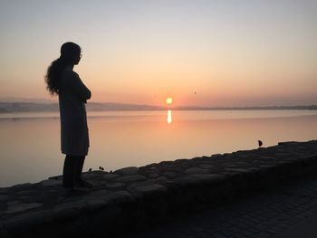 Woman standing on promenade against sky during sunset