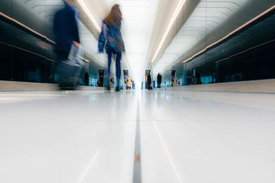 Travelers walking to the departure gate through the bright airport hall