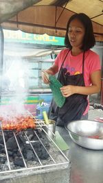 Woman standing on barbecue grill