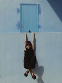 Portrait of smiling young woman standing against wall