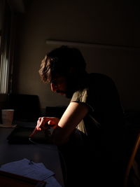 Side view of man using mobile phone at home