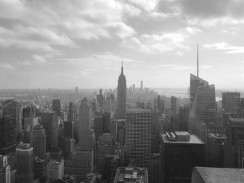 Aerial view of buildings in city against cloudy sky