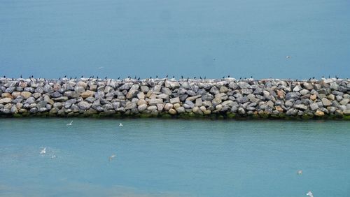 Stone wall by sea against blue sky