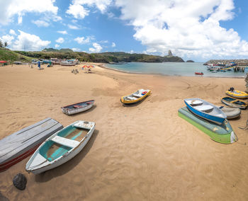 Boats moored at beach against sky