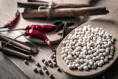 High angle view of white peppercorns with spices on cutting board