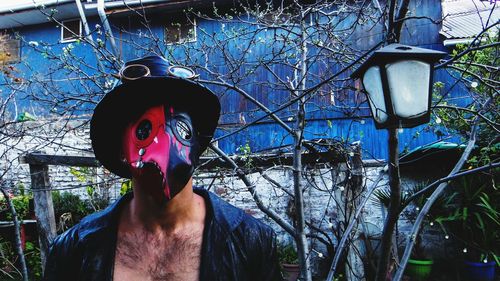 Man wearing mask against bare trees