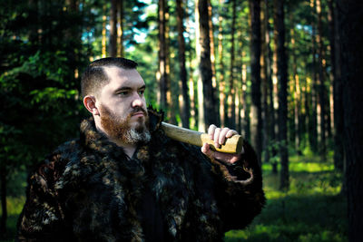 Man with axe standing against trees