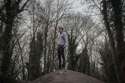 Low angle view of man standing on rock in forest