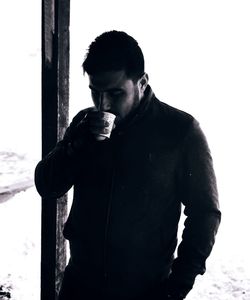 Young man looking away while standing on glass