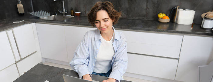 Portrait of young woman using mobile phone at home