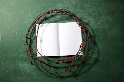 Directly above shot of rusty barbed wire with book on blackboard