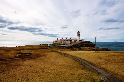 Lighthouse on beach against sky