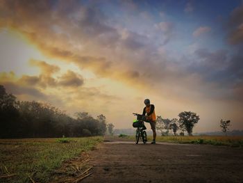 Full length of man with bicycle standing on road against sky