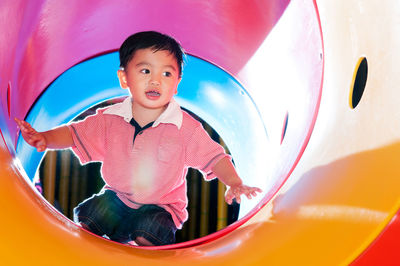 Happy boy playing in slide at amusement park