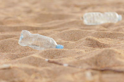 Close-up of water bottle on sand