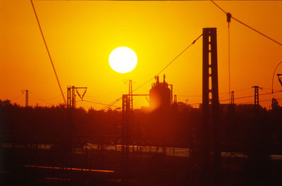 Silhouette cranes at construction site during sunset