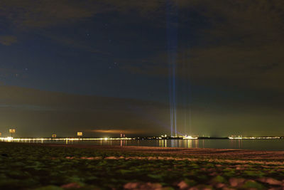 Illuminated lights on land against sky at night