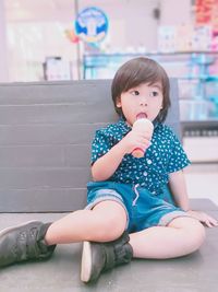 Thoughtful boy eating ice cream cone while sitting on bench