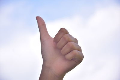 Close-up of human hand against sky