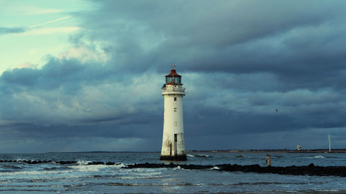 Lighthouse by sea against sky