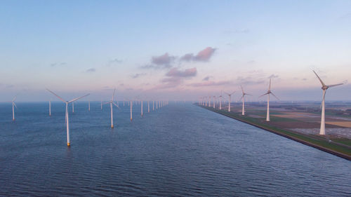 Wind turbines in sea against sky during sunset, windmill turbines in the netherlands 