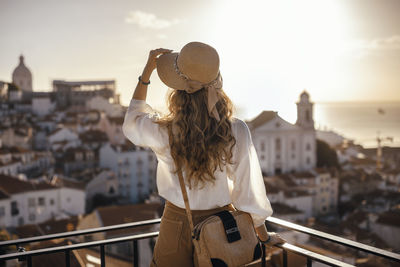 Rear view of woman standing against sky in city