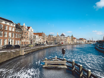 Canal amidst buildings in city against sky