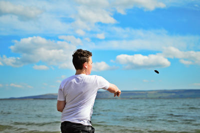 Rear view of boy standing at beach