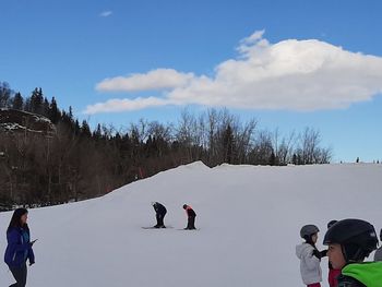 People on snow covered mountain against sky