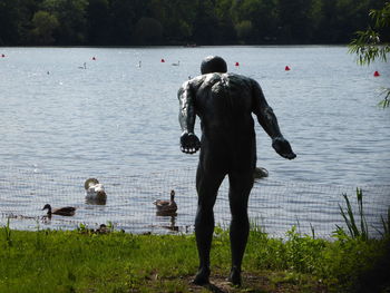 Rear view of people standing at lakeshore