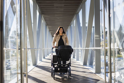 View of woman on parental leave pushing pram through elevated walkway