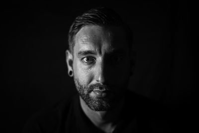 Close-up portrait of young man against black background