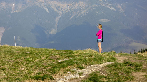 Side view of woman standing on land against mountain