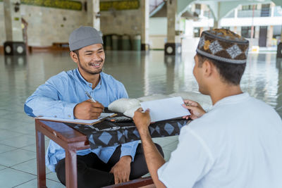 High angle view of men receiving rice bag at mosque