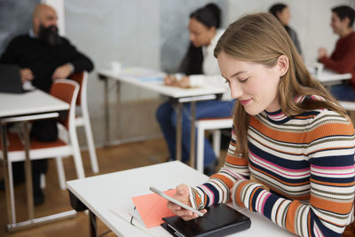 Young woman using cell phone at workshop