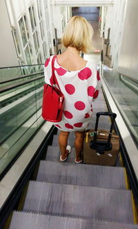 Rear view of woman standing on escalator