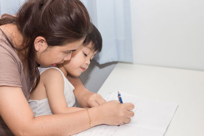 Mother assisting son with homework at home