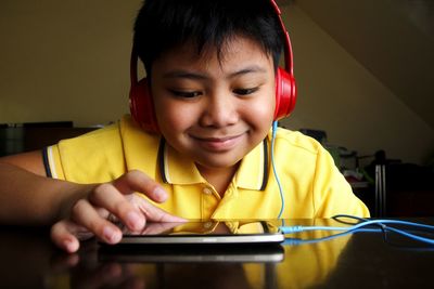 Close-up of boy listening to headphones while using smart phone