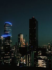 Illuminated buildings in city against sky at night