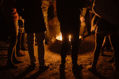 Low section of people standing by bonfire at night