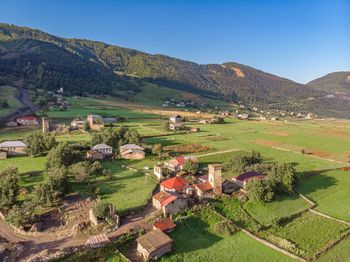 Scenic view of agricultural field by houses against sky