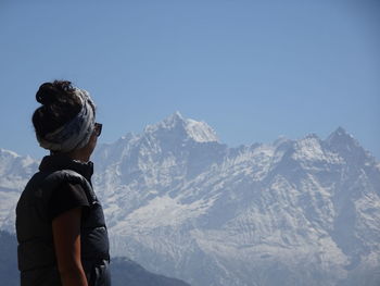 Woman looking at snowcapped mountain against clear sky