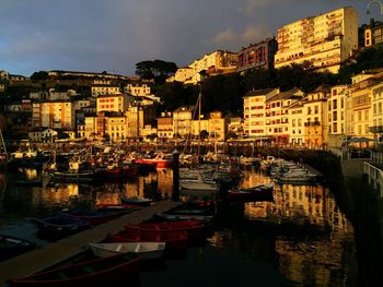 Boats moored on water in city against sky