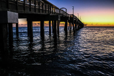 Pier on sea against sky during sunset