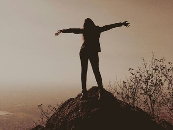 Silhouette of woman standing against sky at sunset
