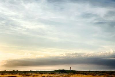 Man standing on field against sky during sunset